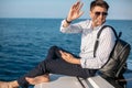 Man in sunglasses and trendy clothes sailing on motor boat