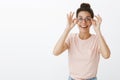 Positive and charismatic good-looking young european female student putting on new transparent glasses smiling broadly