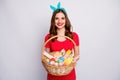 Positive cheerful girl hold big wicker easter basket painted eggs colorful shape bunny confectionery pastries cookies Royalty Free Stock Photo