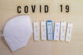 Six positive corona rapid tests lie next to a medical face mask and above them is the word Covid 19