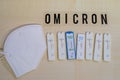 6 positive corona rapid tests lie next to a medical face mask and above them is the word Omicron