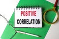 POSITIVE CORRELATION text on notebook on green paper
