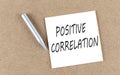 POSITIVE CORRELATION text on a sticky note on cork board with pencil Royalty Free Stock Photo
