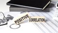 POSITIVE CORRELATION - text on a wooden block with chart and notebook