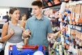 Positive couple customers chooses paint brushes on shelves of hardware store Royalty Free Stock Photo