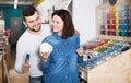 positive couple examining various paints in paint store Royalty Free Stock Photo