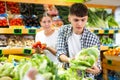 Positive couple standing together in fruit and vegetable section of supermarket and choosing vegetables Royalty Free Stock Photo