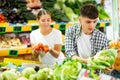 Positive couple standing together in fruit and vegetable section of supermarket and choosing vegetables Royalty Free Stock Photo