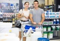 Positive couple walking with shopping trolley cart in hardware store Royalty Free Stock Photo