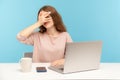 Positive curious woman employee sitting at workplace with laptop and spying, looking through fingers with interest