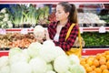 Positive customer chooses cabbages at grocery store