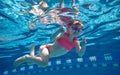 Positive, cute, little baby girl, toddler in pink swimsuit and goggles diving, swimming underwater in swimming pool Royalty Free Stock Photo
