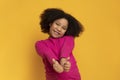 Positive cute little girl gesturing thumbs up and smiling at camera