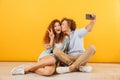 Positive cute people man and woman 20s sitting on floor together Royalty Free Stock Photo