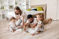 Positive dad, mommy, kids painting with brushes while sitting on the floor Royalty Free Stock Photo