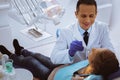Positive delighted dentist sitting near patient