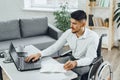 Positive disabled young man in wheelchair working in office Royalty Free Stock Photo