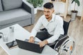 Positive disabled young man in wheelchair working in office Royalty Free Stock Photo