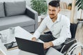 Positive disabled young man in wheelchair working in office Royalty Free Stock Photo