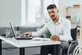 Positive disabled young man in wheelchair working in office Royalty Free Stock Photo