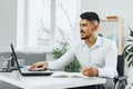 Positive disabled young man in wheelchair working in office Royalty Free Stock Photo