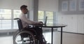 Positive disabled young man in wheelchair working in office Royalty Free Stock Photo