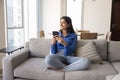 Positive dreamy young Indian woman using mobile phone at home Royalty Free Stock Photo