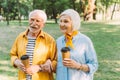 Positive elderly couple holding disposable cups