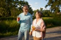 Positive elderly couple with refreshment cocktail walking outdoors