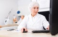 Elderly female cosmetologist working with laptop in aesthetic medicine office