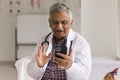 Positive elderly Indian medical professional man talking on video call Royalty Free Stock Photo