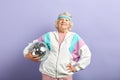 Positive elderly lady holds sparkling disco ball, dressed smiling at camera. Royalty Free Stock Photo