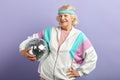 Positive elderly lady holds sparkling disco ball, dressed smiling at camera. Royalty Free Stock Photo