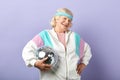 Positive elderly lady holds sparkling disco ball, dressed smiling at camera. Royalty Free Stock Photo