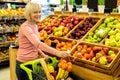 Positive elderly lady shopping at huge supermarket, buying fruits Royalty Free Stock Photo