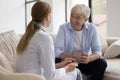 Positive elderly man consulting young doctor woman at home Royalty Free Stock Photo