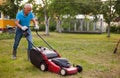Positive elderly man with lawnmower when mowing the lawn