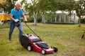 Positive elderly man with lawnmower when mowing the lawn Royalty Free Stock Photo