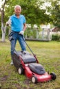 Positive elderly man with lawnmower when mowing the lawn Royalty Free Stock Photo