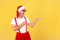 Positive elderly man in sunglasses and santa claus hat pointing finger showing freespace, advertisement area