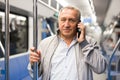 Positive elderly passenger communicates on mobile phone in subway car