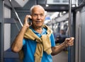 Positive elderly passenger talking on mobile phone in subway car