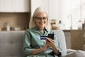 Positive elderly retired woman using online bank application on smartphone