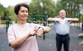 Elderly woman looking at her smart bracelet in open-air sports area Royalty Free Stock Photo