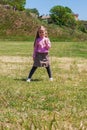 Positive emotional young lady with long blond hair smiles, looks on dandelion flower that holds in hand Royalty Free Stock Photo