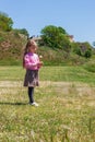 Positive emotional young lady with long blond hair smiles, looks on dandelion flower that holds in hand Royalty Free Stock Photo