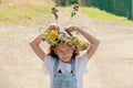 Cute pretty smiling girl with a wreath of wild flowers. Summer vacation outside the city. Rest and relaxation in the village. Royalty Free Stock Photo