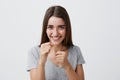 Positive emotions. Happy young handsome joyful girl with long brown hair in casual plain t-shirt laughing, holding hands Royalty Free Stock Photo