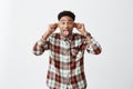 Positive emotions. Portrait of young dark-skinned attractive man with afro hairdo in casual checkered shirt holding ears Royalty Free Stock Photo