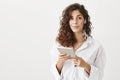 Positive emotive european female holding tablet and wearing wireless earbud while smiling and expressing happiness